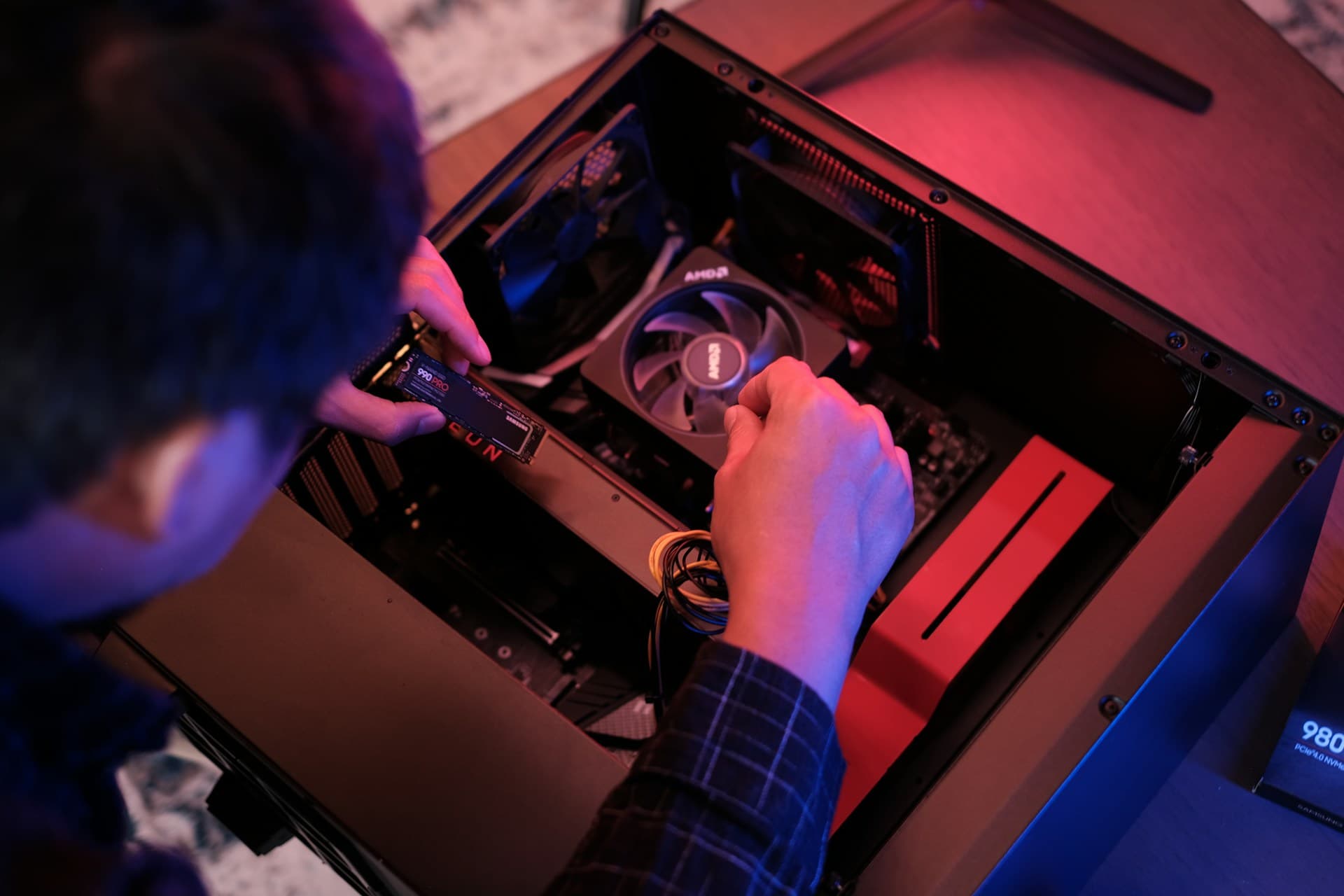 Person installing a Samsung 990 Pro M.2 NVMe SSD into a desktop PC motherboard
