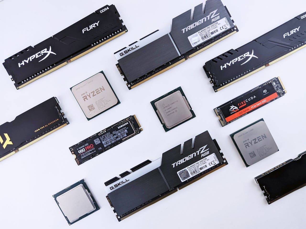 PC upgrade components laid out including RAM sticks, AMD and Intel CPUs, and NVMe SSDs on a white background