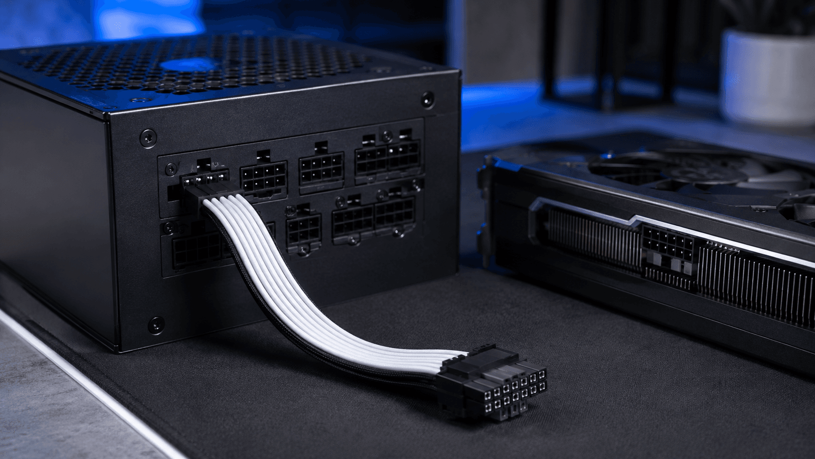 A modular power supply with its native 12V-2x6 (12VHPWR) cable connected, laid out next to a graphics card before installation